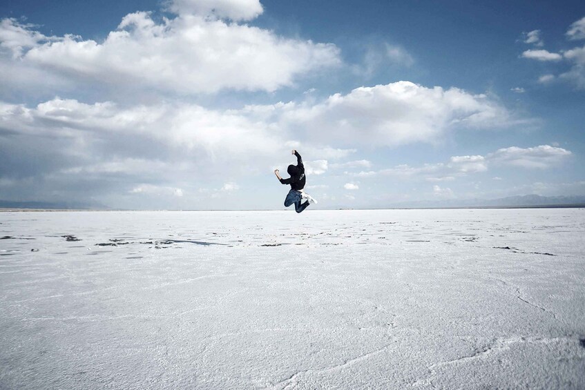 A person jumping in a snowy landscape with a clear sky. 1