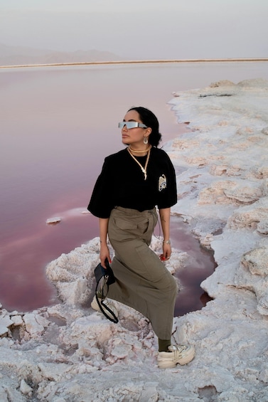 A person standing on a salt flat with pink water. 3