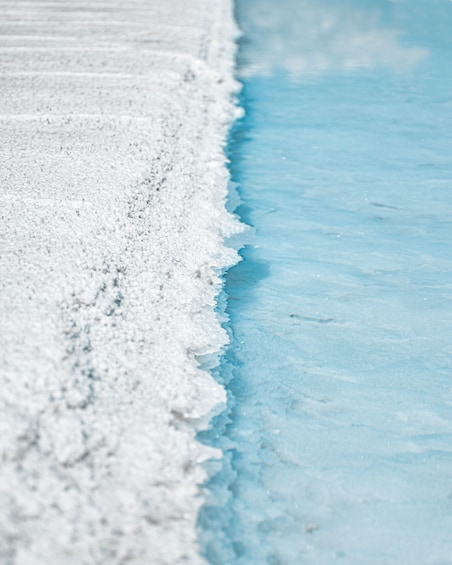 A close-up of a snowy beach with a clear blue waterline. 2