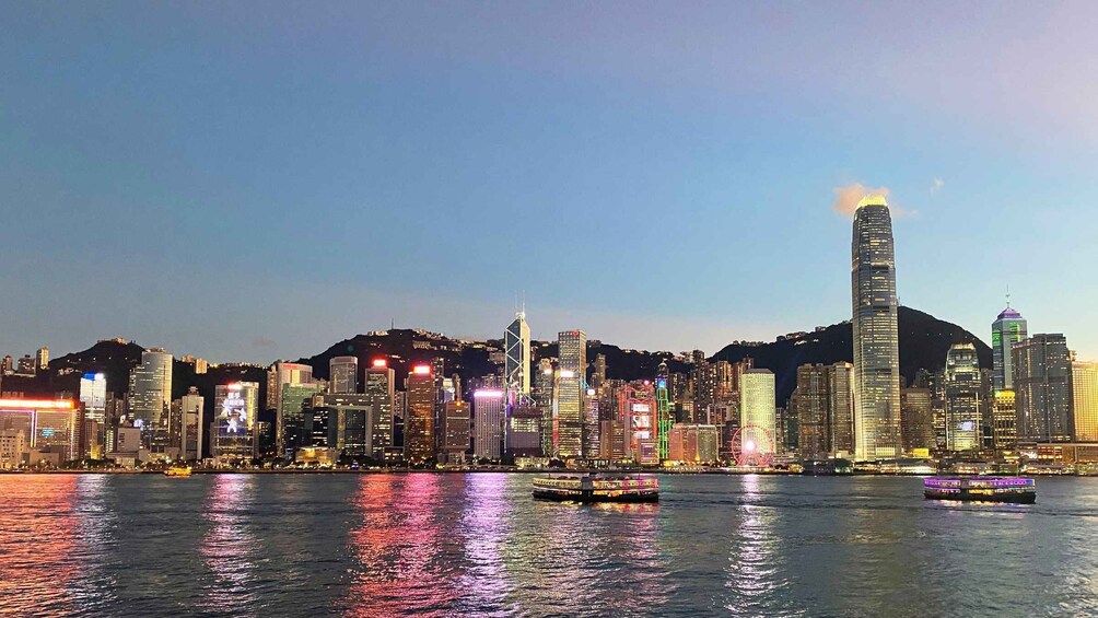 A city skyline at dusk with illuminated buildings and a river reflecting lights. 2