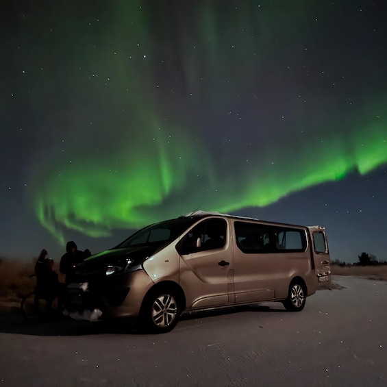 A van parked on a road with the Northern Lights in the background. 5