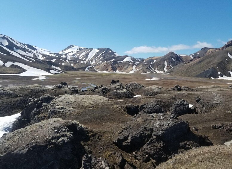 A mountainous landscape with snow patches and rocky terrain. 1
