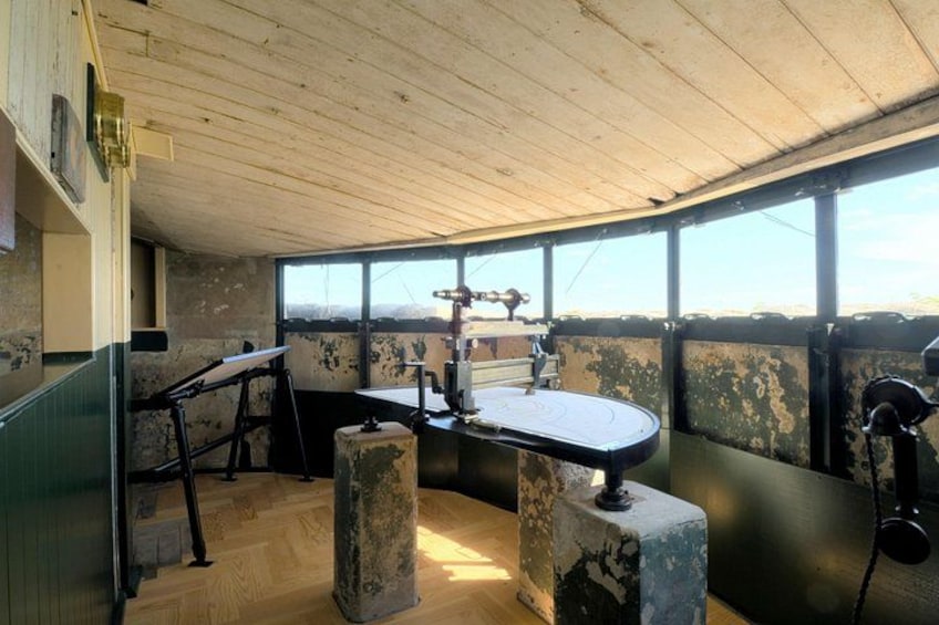 A rustic cabin interior with a wooden ceiling, a workbench, and a large window overlooking a landscape. 3