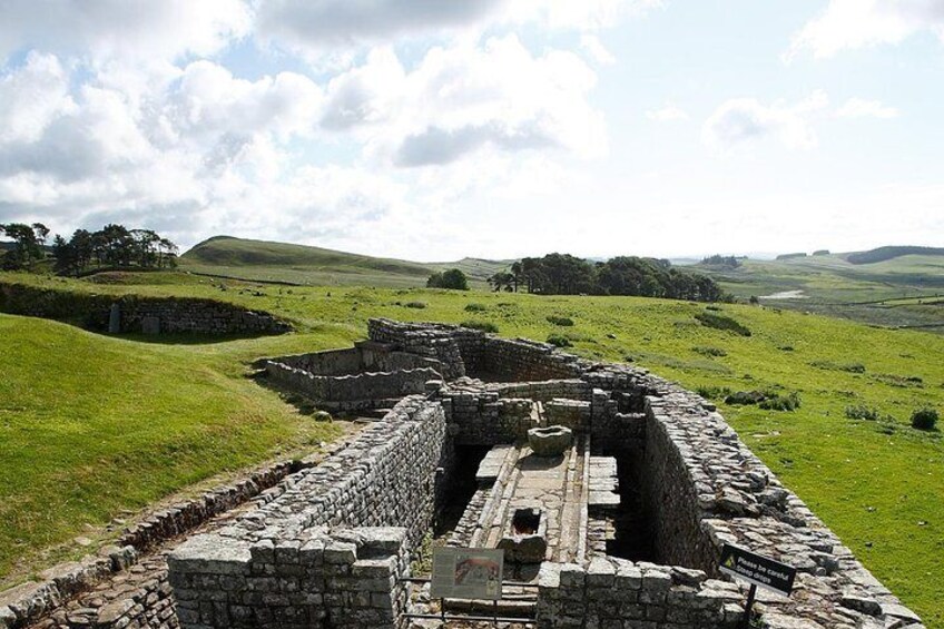 Ancient stone ruins with a grassy landscape and rolling hills in the background. 4