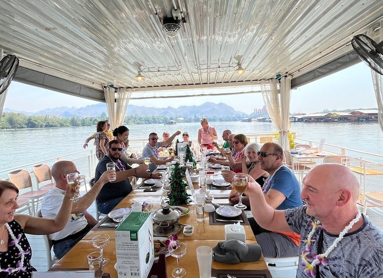 A group of people dining on a boat with a view of a lake and mountains in the background. 3
