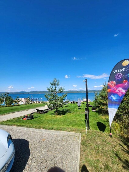 A coastal view with a grassy area, a parked car, and a banner with the text 'I'USE.' 5