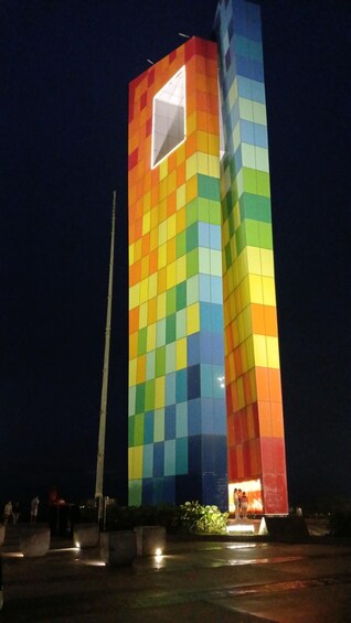 A tall building with a colorful checkered facade at night. 3