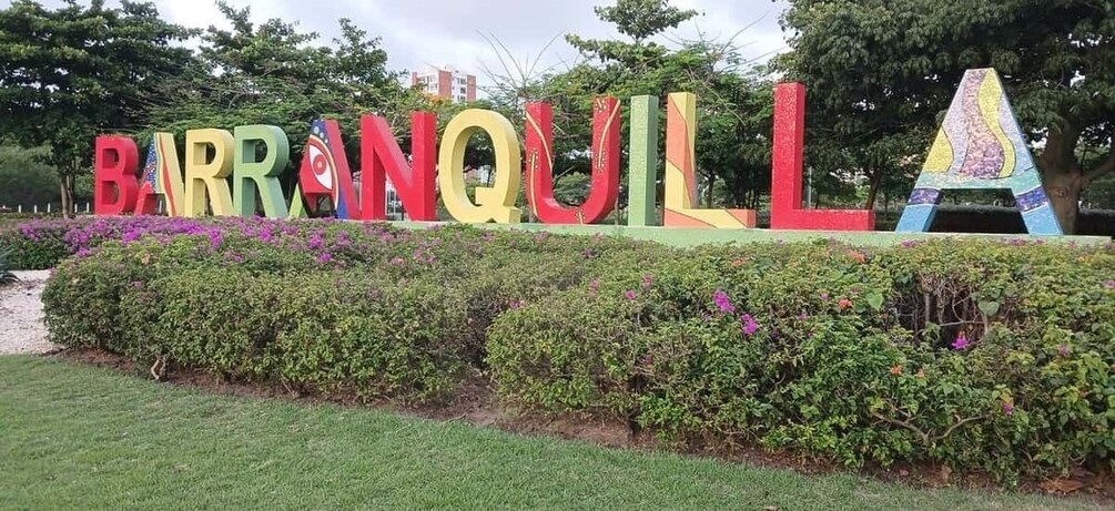 A colorful sign with the name 'BARRANQUILLA' in large letters, surrounded by well-maintained hedges and a grassy area. 4
