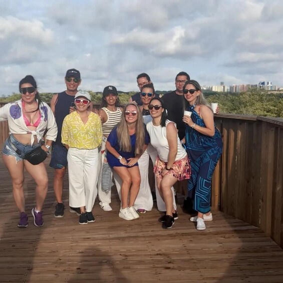 A group of people posing on a wooden deck with a city skyline in the background. 1