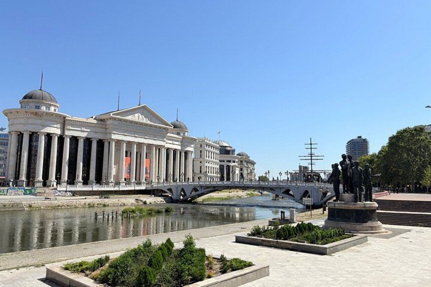 A classical building with columns, a bridge, and a statue. 1