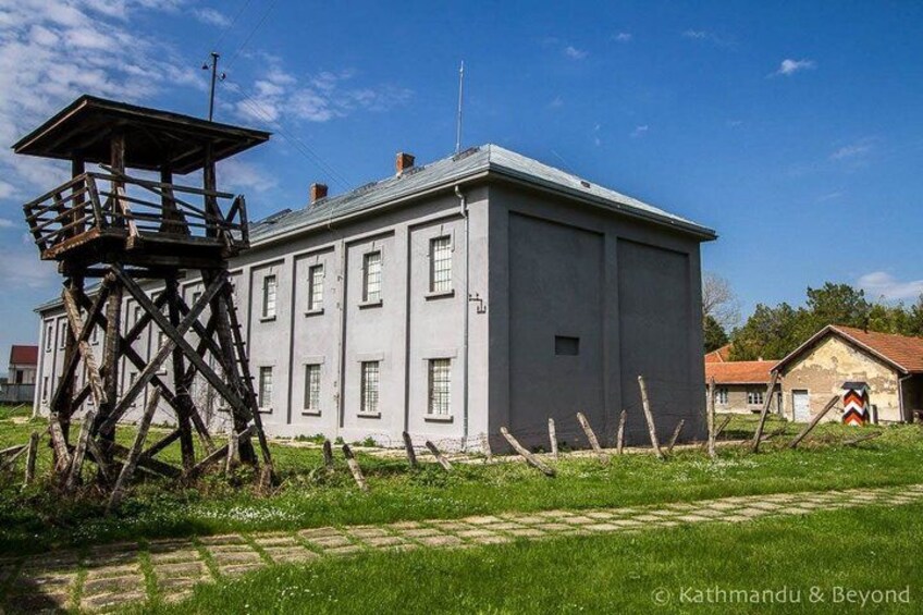 A large, single-story building with a wooden tower structure in front. 3