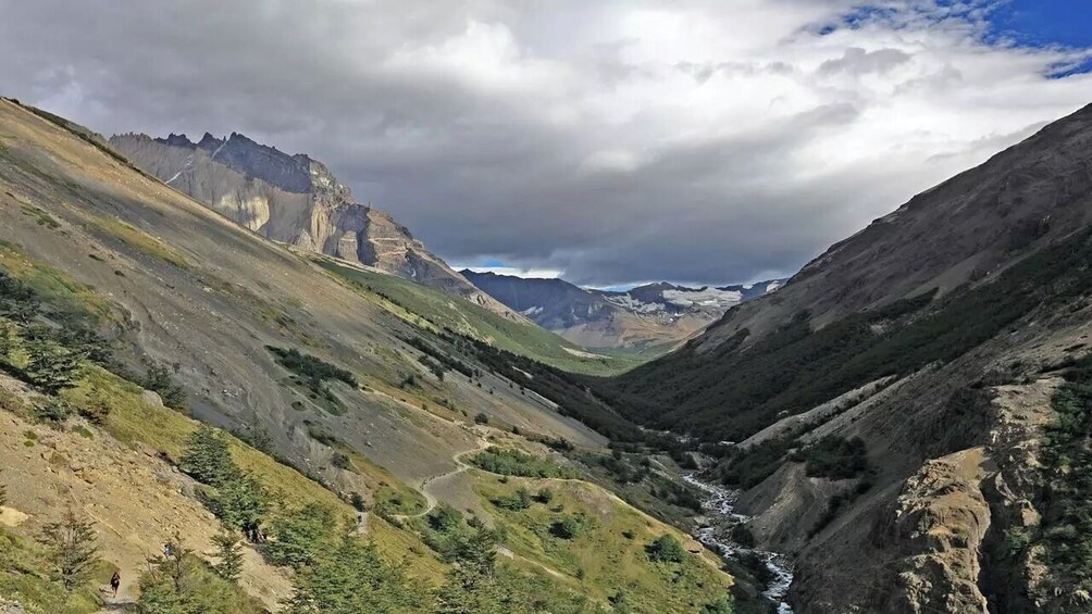 A valley with a river, steep cliffs, and a mountain range in the distance. 3