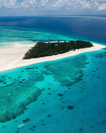 A turquoise sea with a white sandy beach and a small island with dense vegetation. 2