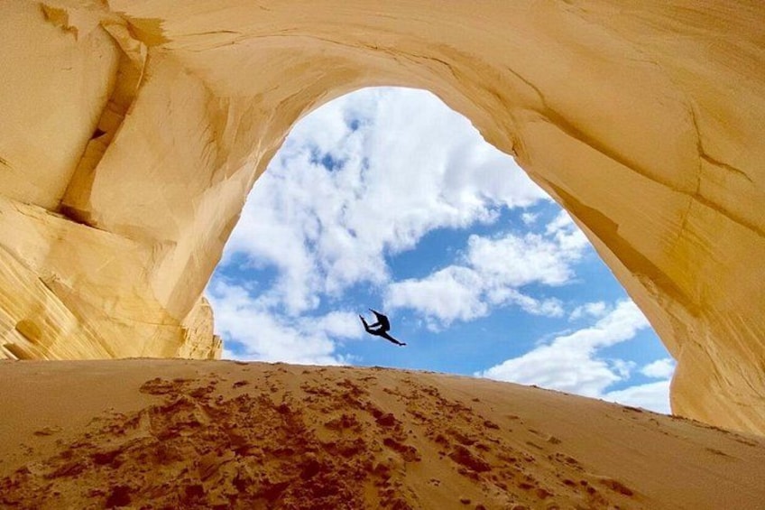 A person jumping through a natural rock arch. 1