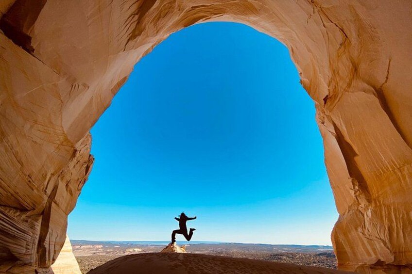 Una persona salta attraverso un arco naturale di roccia. 3