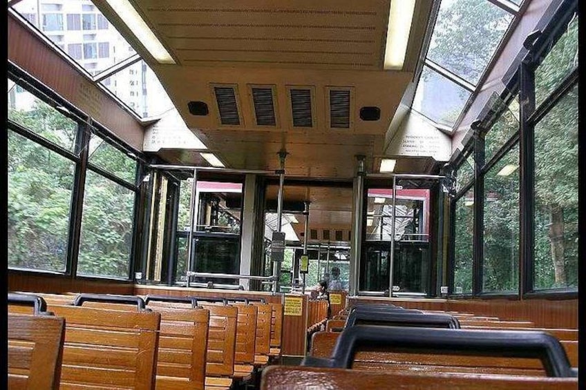 A bus interior with wooden seats, large windows, and a ceiling with ventilation. 4