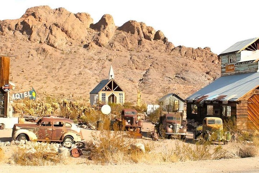 Paisaje desértico con una iglesia, un motel y coches antiguos. 2