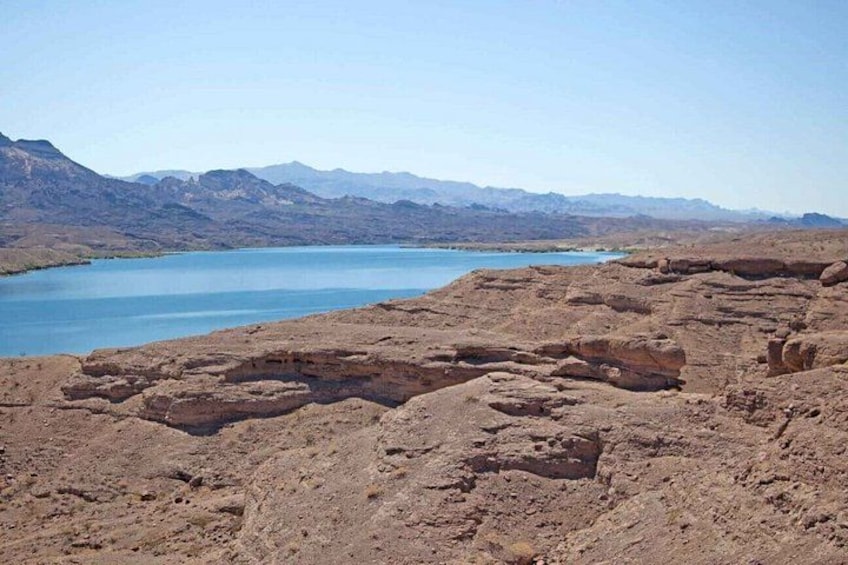 Lecho de lago seco con rocas dispersas y un cuerpo de agua a lo lejos. 5