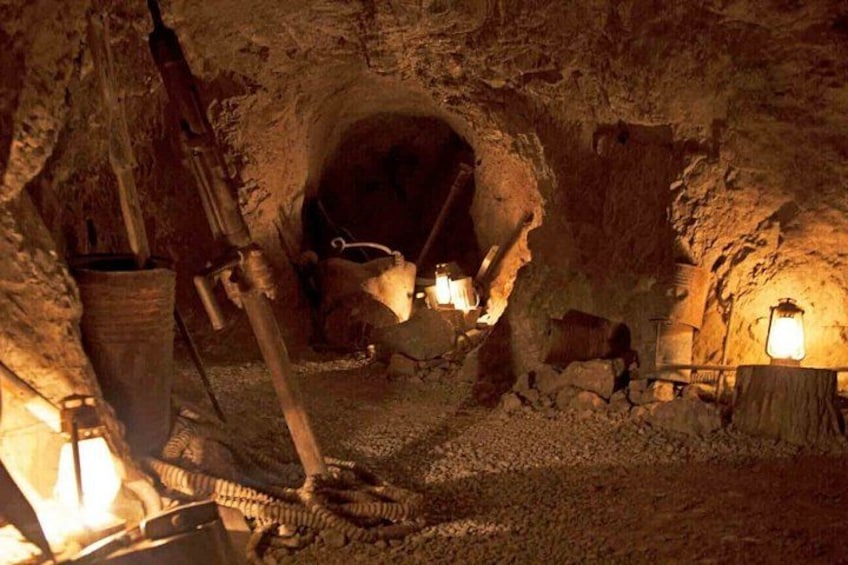 Un túnel minero subterráneo con estructuras de madera, herramientas de minería y un farol. 3