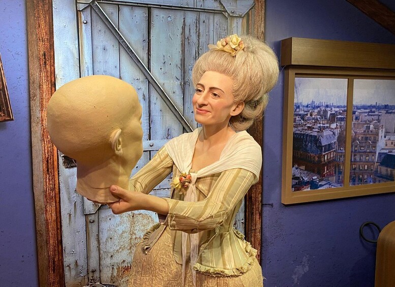 A person in historical attire holding a mannequin head. 2