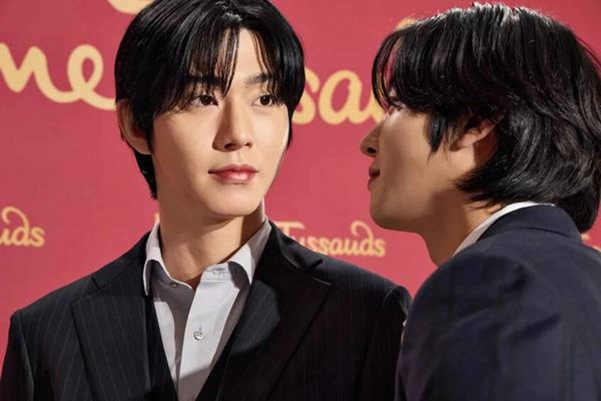 Two individuals in suits at an event with a red backdrop and the word 'Tissandras' visible. 1