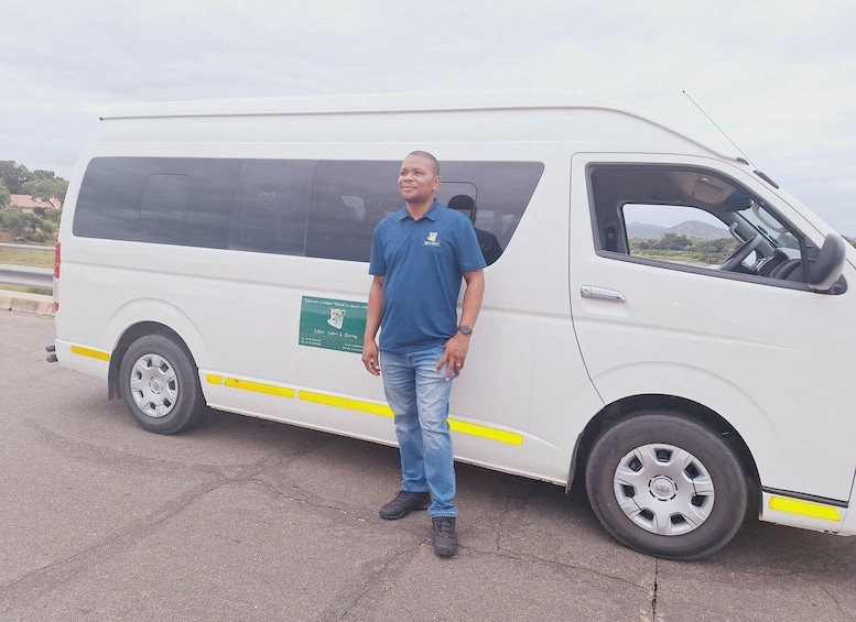 A man standing next to a white van with a green advertisement on the side. 1