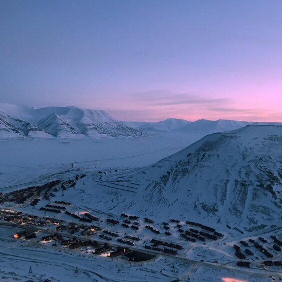 A snow-covered mountainous landscape with a small settlement at its base. 5