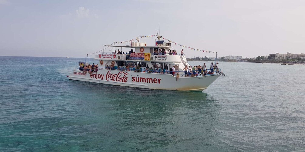 A boat with 'enjoy Coca-Cola summer' written on its side, sailing on calm waters. 1