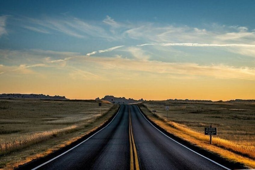 Une route droite, bordée de champs à perte de vue, avec un panneau indiquant la limite de vitesse, le tout sous un ciel dégagé. 2