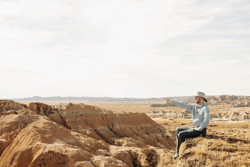 Une personne assise sur une colline, dans un paysage aride et rocheux où la végétation est rare. 3