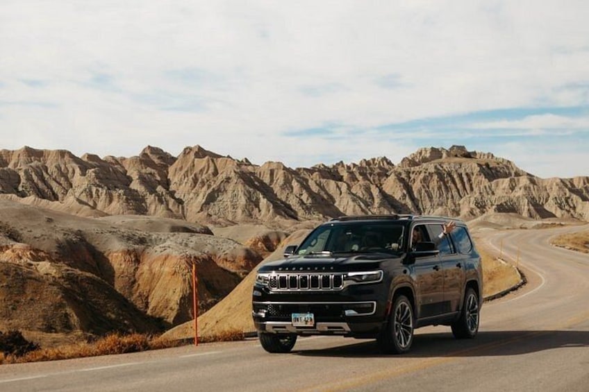 A vehicle on a winding road with a mountainous backdrop. 2