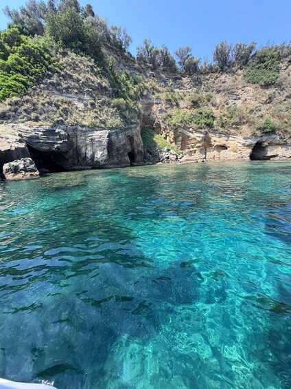 Clear turquoise water, rocky cliffs, and sparse vegetation. 1
