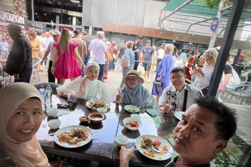 Un groupe de personnes est réuni autour de tables à l’extérieur pour prendre un repas. 3