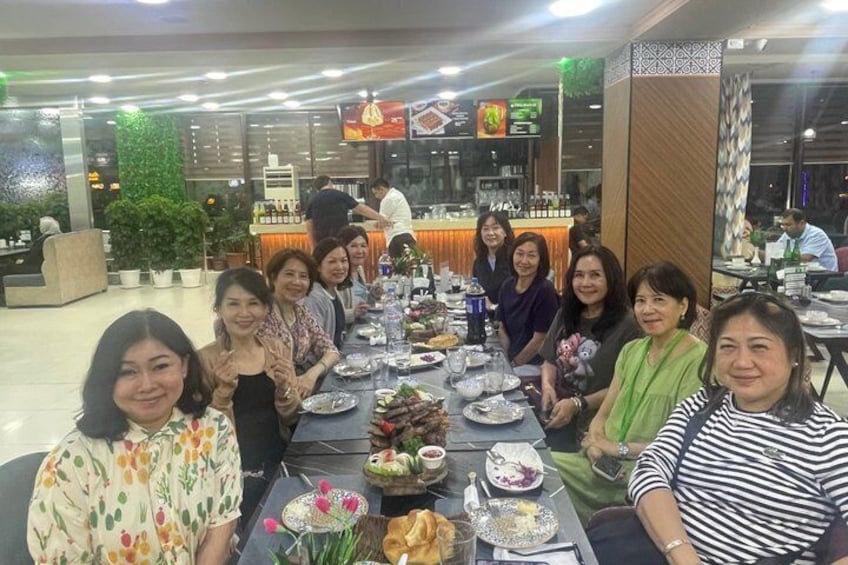 Un groupe de personnes est assis à une table dans un restaurant, devant divers plats et boissons. 5