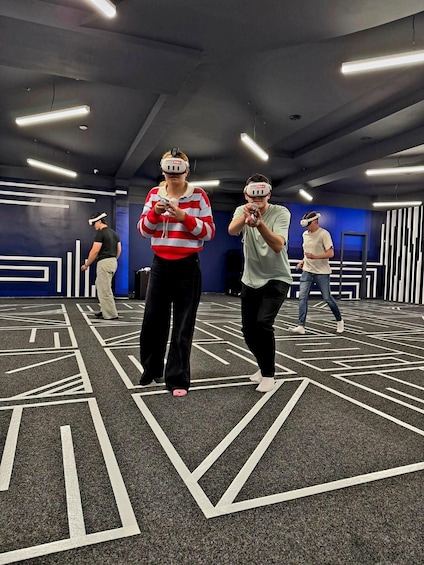 People using VR headsets in a room with geometric carpet patterns and blue walls. 2
