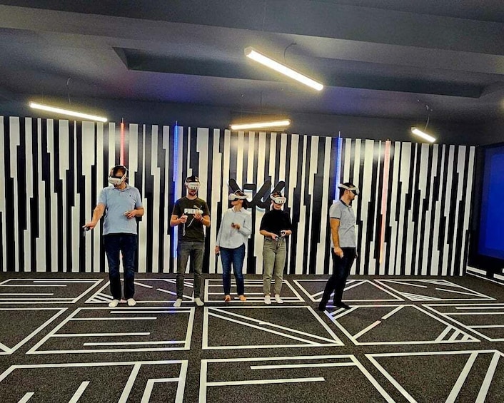 A group of people wearing VR headsets in a room with a striped wall and geometric floor design. 4