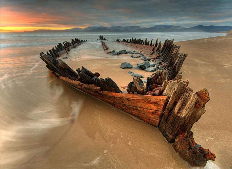 A weathered wooden structure on a beach with a sunset in the background. 3