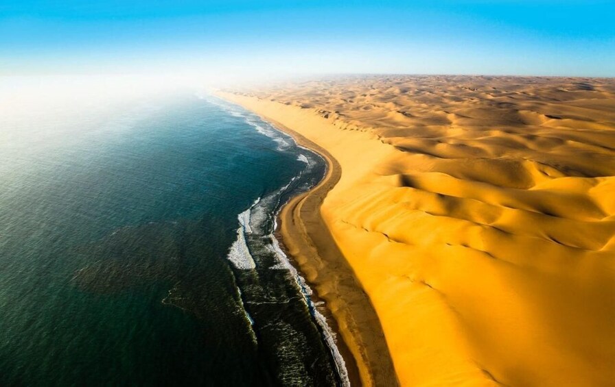 A coastal desert landscape with a sandy beach and dunes. 1