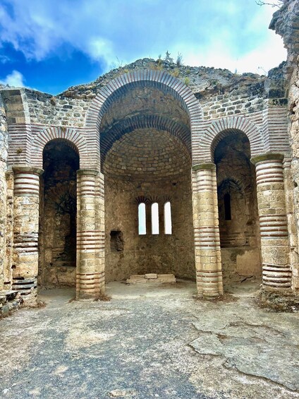 An ancient stone structure with three arches and a central dome. 5