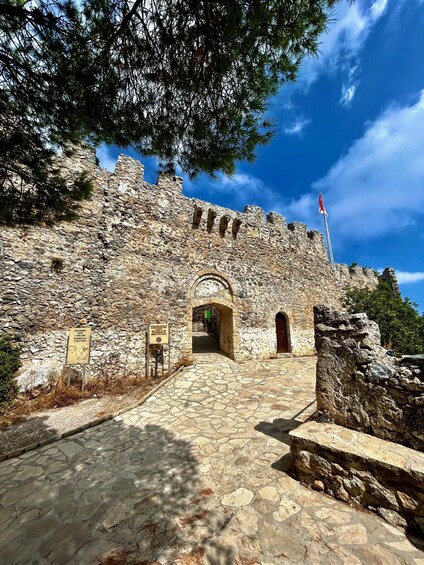 A stone fortress entrance with a clear sky above. 1