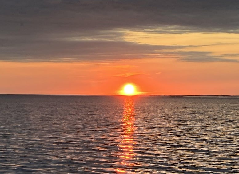 A sunset over a calm sea with a visible sun reflection on the water. 3