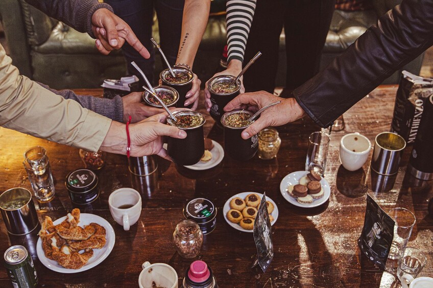 A group of people sharing a meal with various dishes and drinks on a wooden table. 5