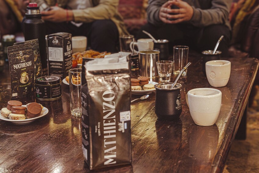A table with coffee beans, a coffee cup, a mug, and a plate of cookies. 4