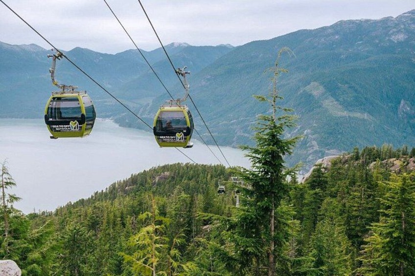 Two cable cars suspended over a lake with mountains in the background. 2