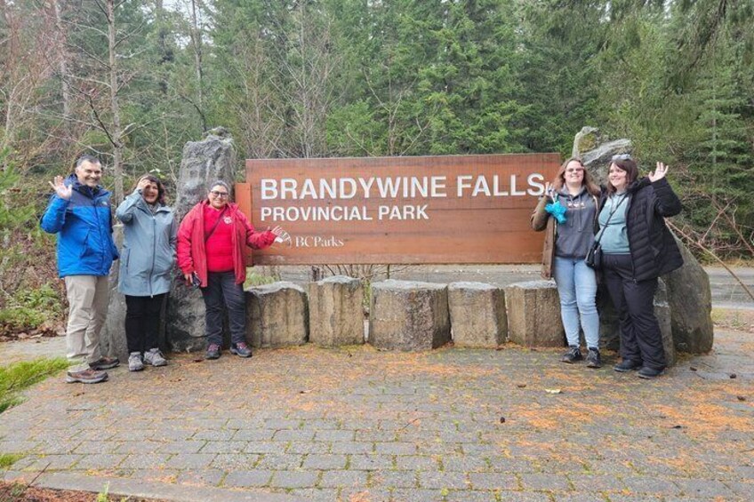 Een groep mensen staat voor een bord met daarop Brandywine Falls Provincial Park. 3
