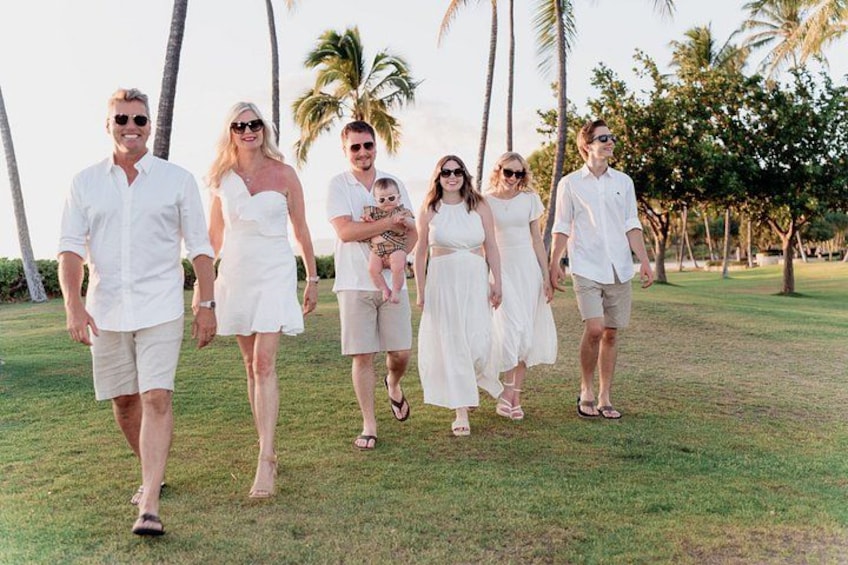 A group of people walking on a grassy field with palm trees in the background. 1