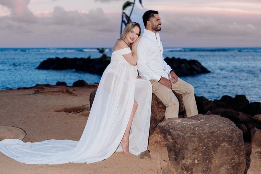 A couple sitting on rocks by the ocean at sunset. 4