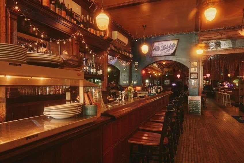 Un bar avec des étagères en bois, des lampes suspendues et une enseigne sur laquelle on peut lire : « Le Bar ». 4