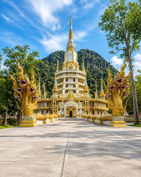 A multi-tiered temple with golden spires and intricate designs, surrounded by lush greenery and a mountainous backdrop. 1