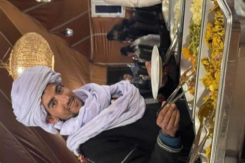 A person in traditional attire holding a tray with a mirror and flowers. 5